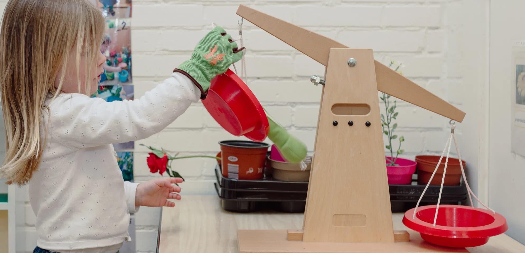 Een kind van de peutergroep speelt met een weegschaal bij kinderopvang Kind&co ludens