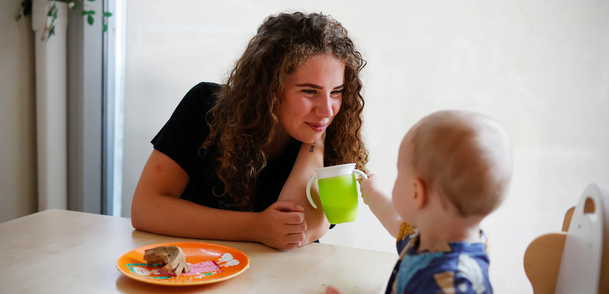 Kind eet samen met pedagogisch medewerker bij kinderopvang Kind&co ludens