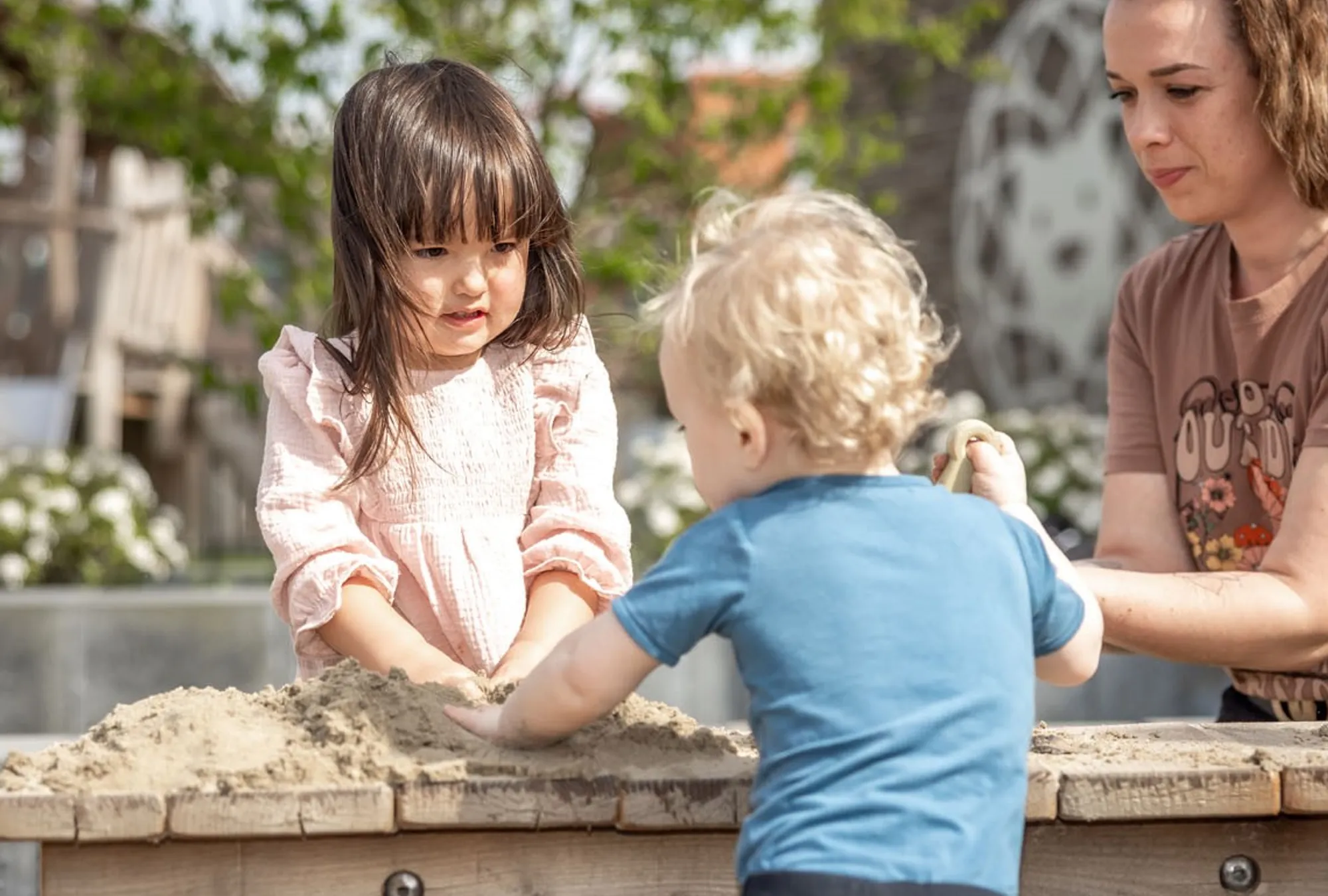 Kinderen spelen in zandbak met pedagogisch medewerker bij Kind&co ludens