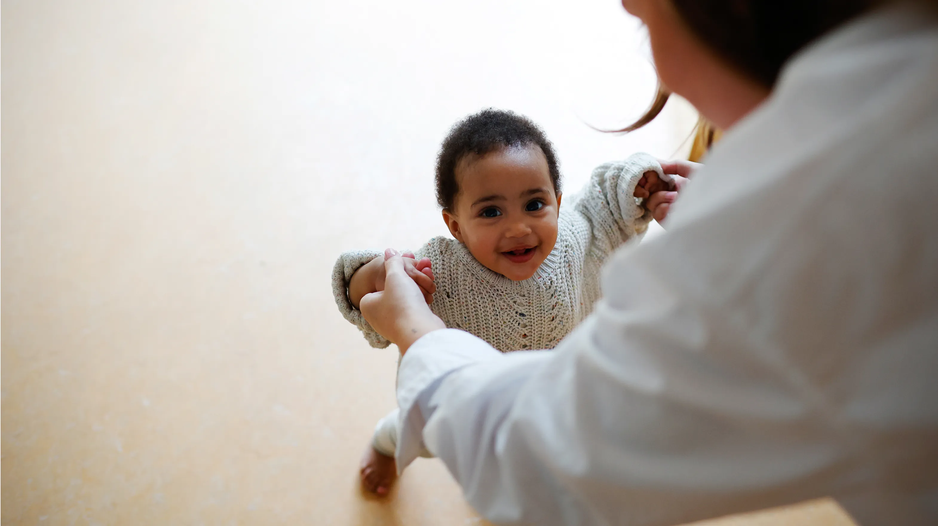 Peuter leert stapjes lopen met pedagogisch medewerker bij kinderopvang Kind&co ludens