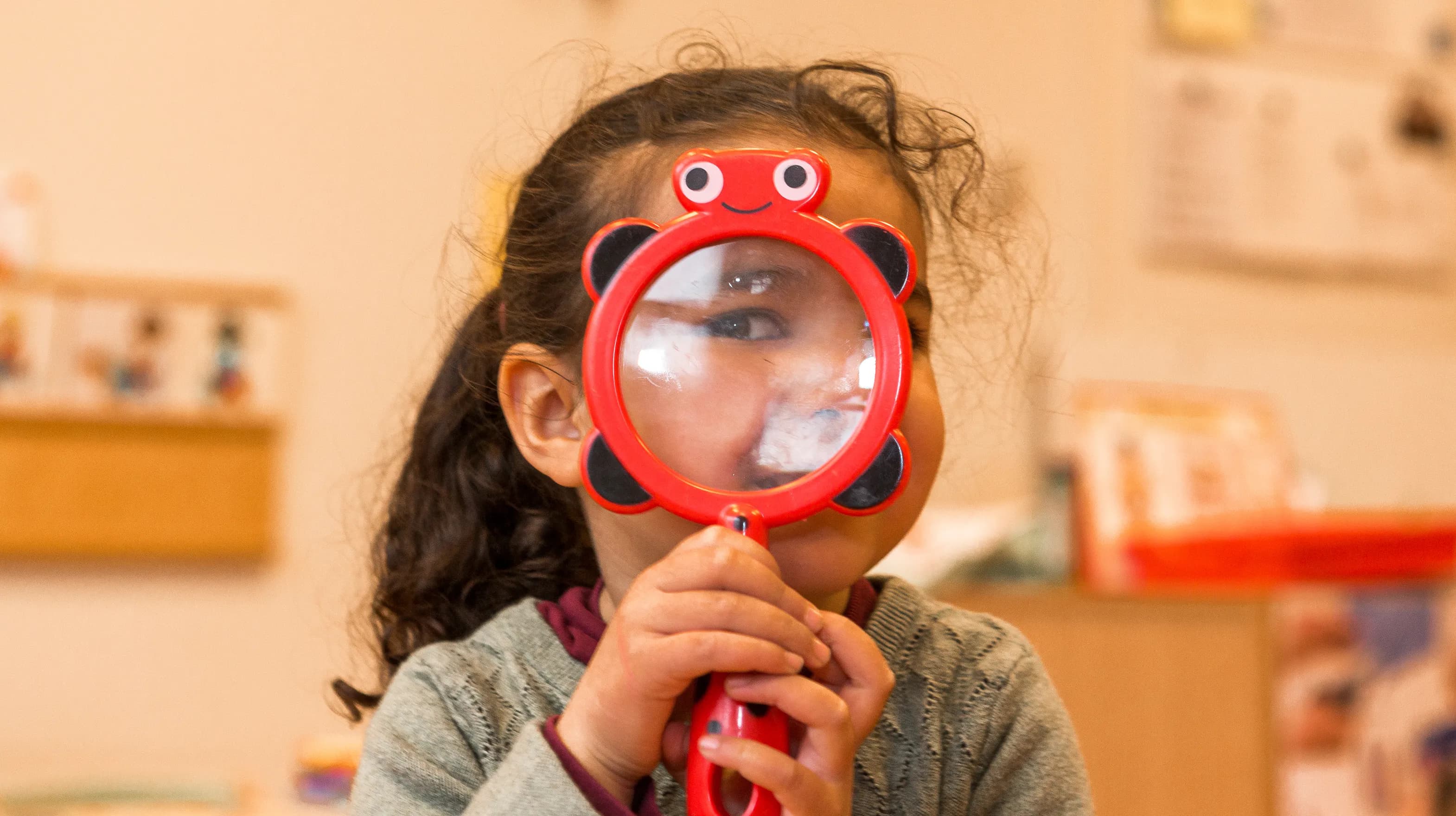 Kind op de peutergroep speelt met vergrootglas bij kinderopvang Kind&co ludens