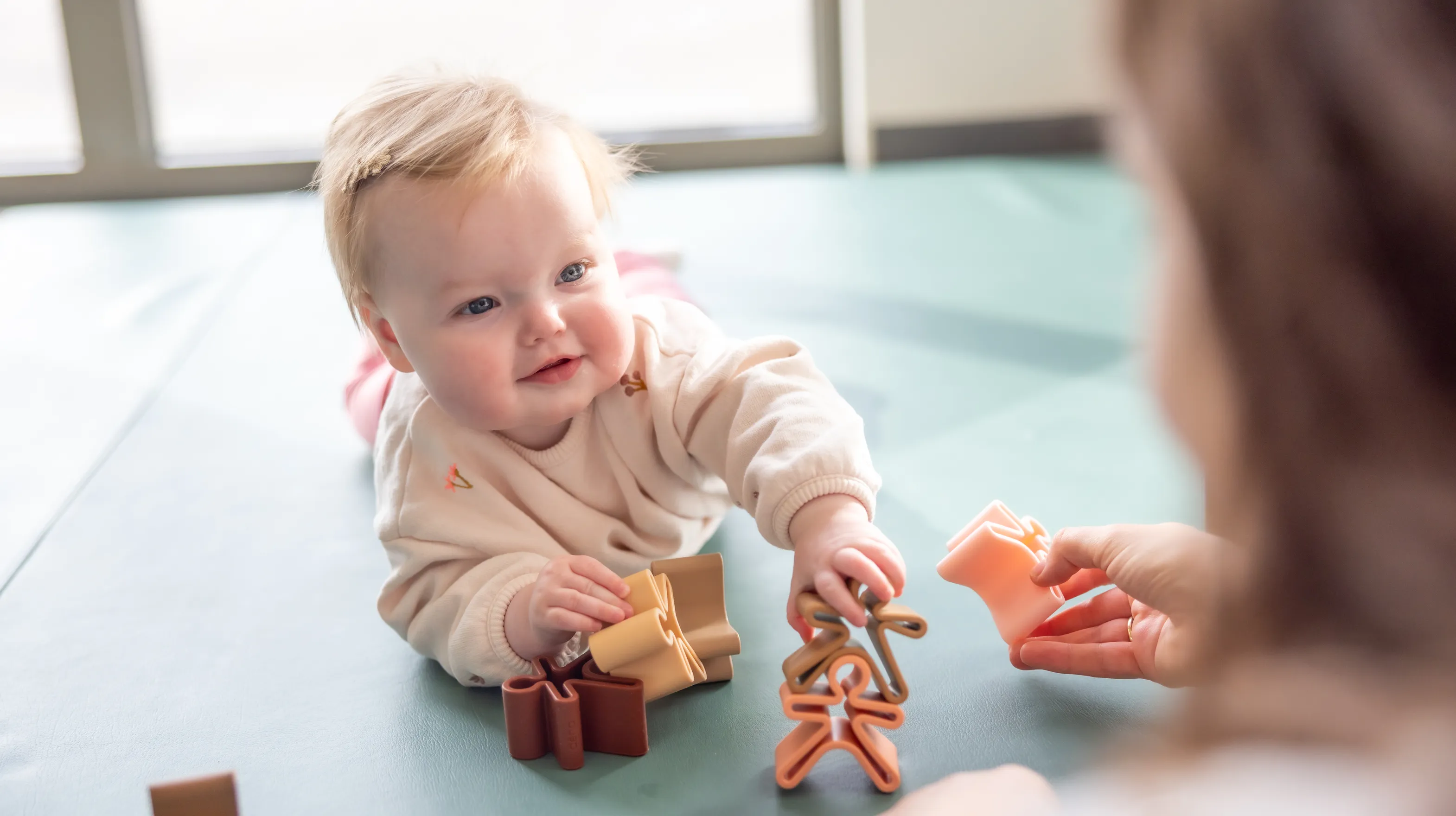 Baby speelt met houten speelgoed poppetjes bij gastouder van kinderopvang Kind&co ludens