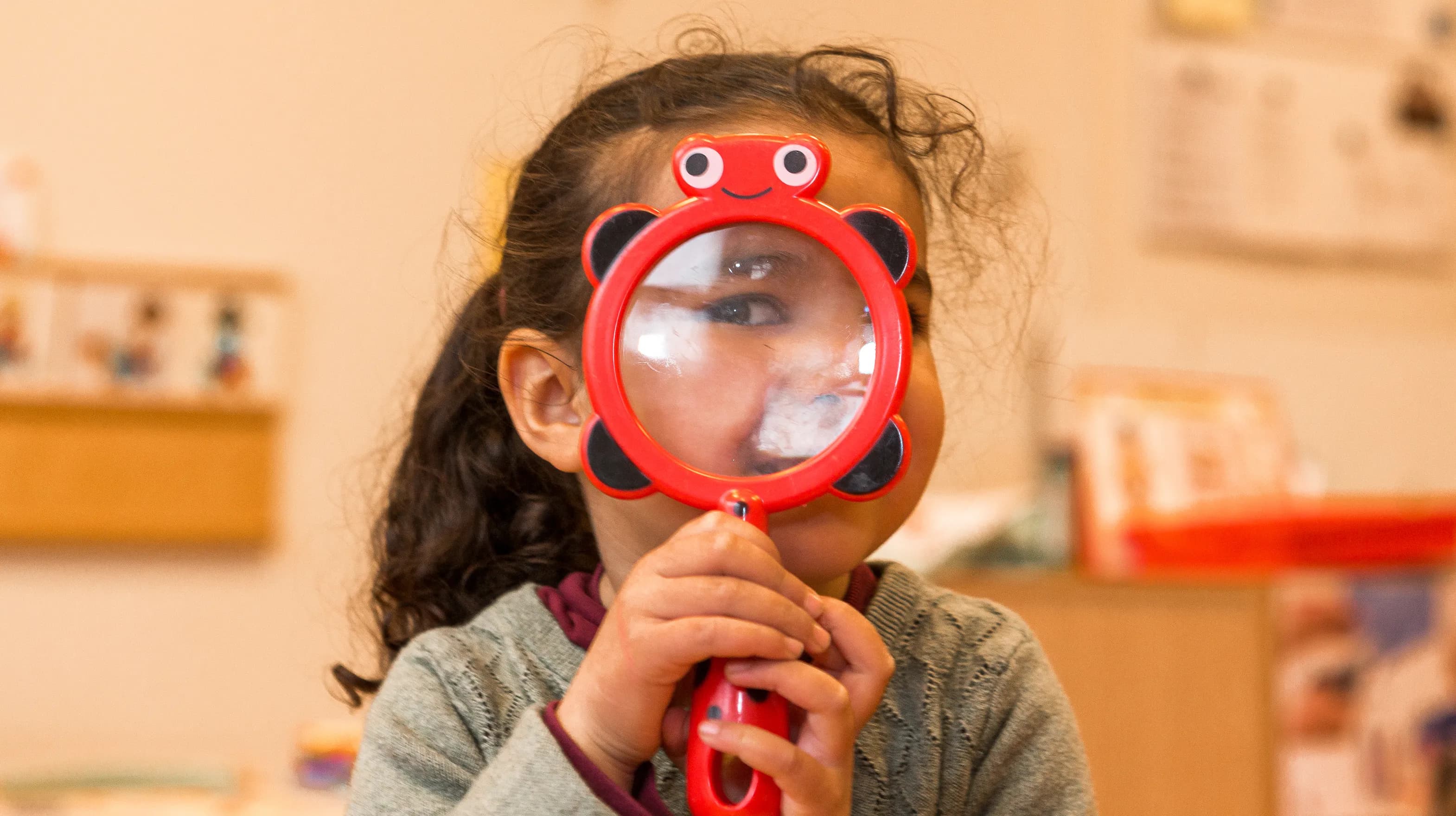 Kind op de peutergroep speelt met vergrootglas bij kinderopvang Kind&co ludens