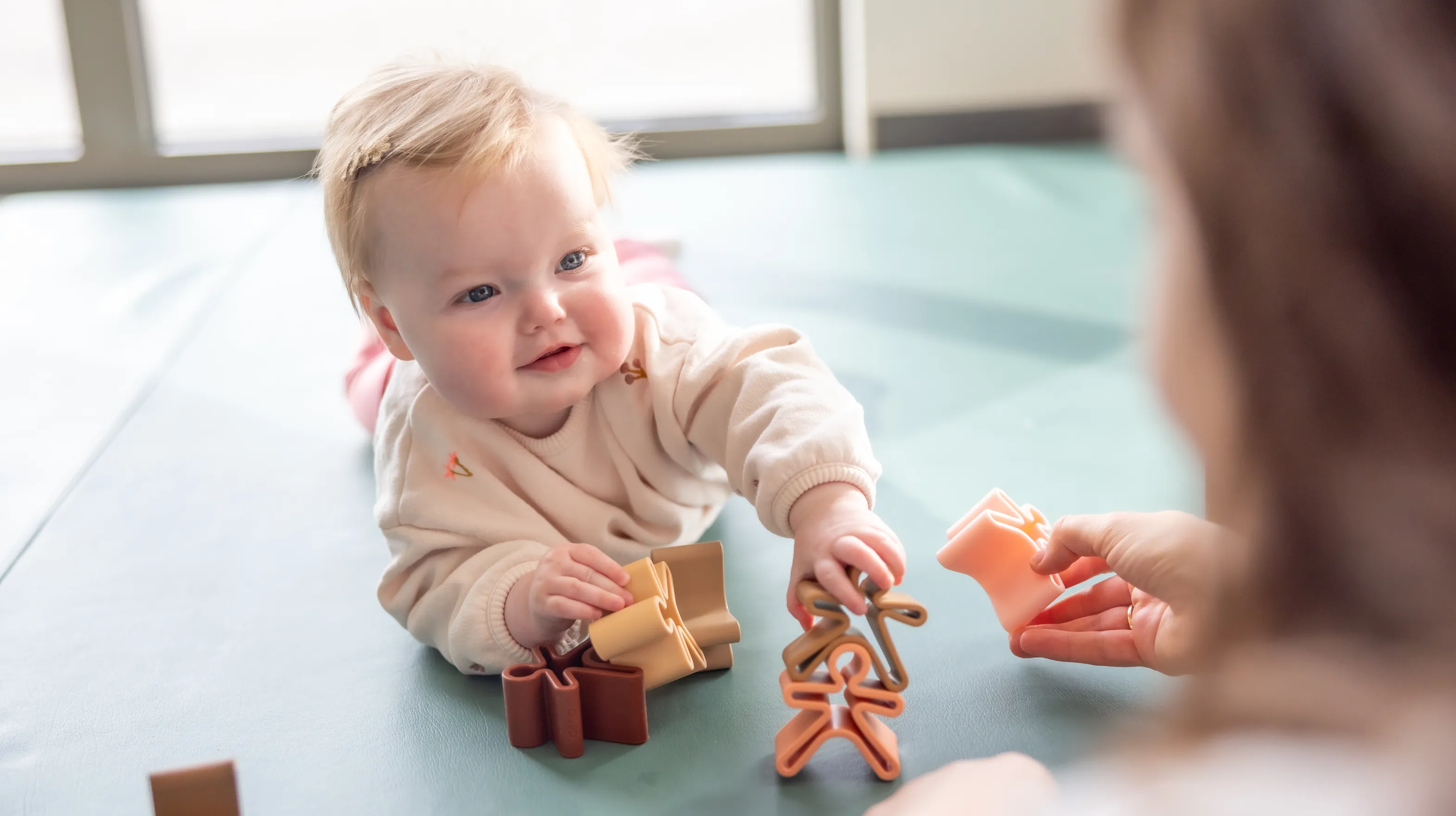Baby speelt met houten speelgoed poppetjes bij gastouder van kinderopvang Kind&co ludens