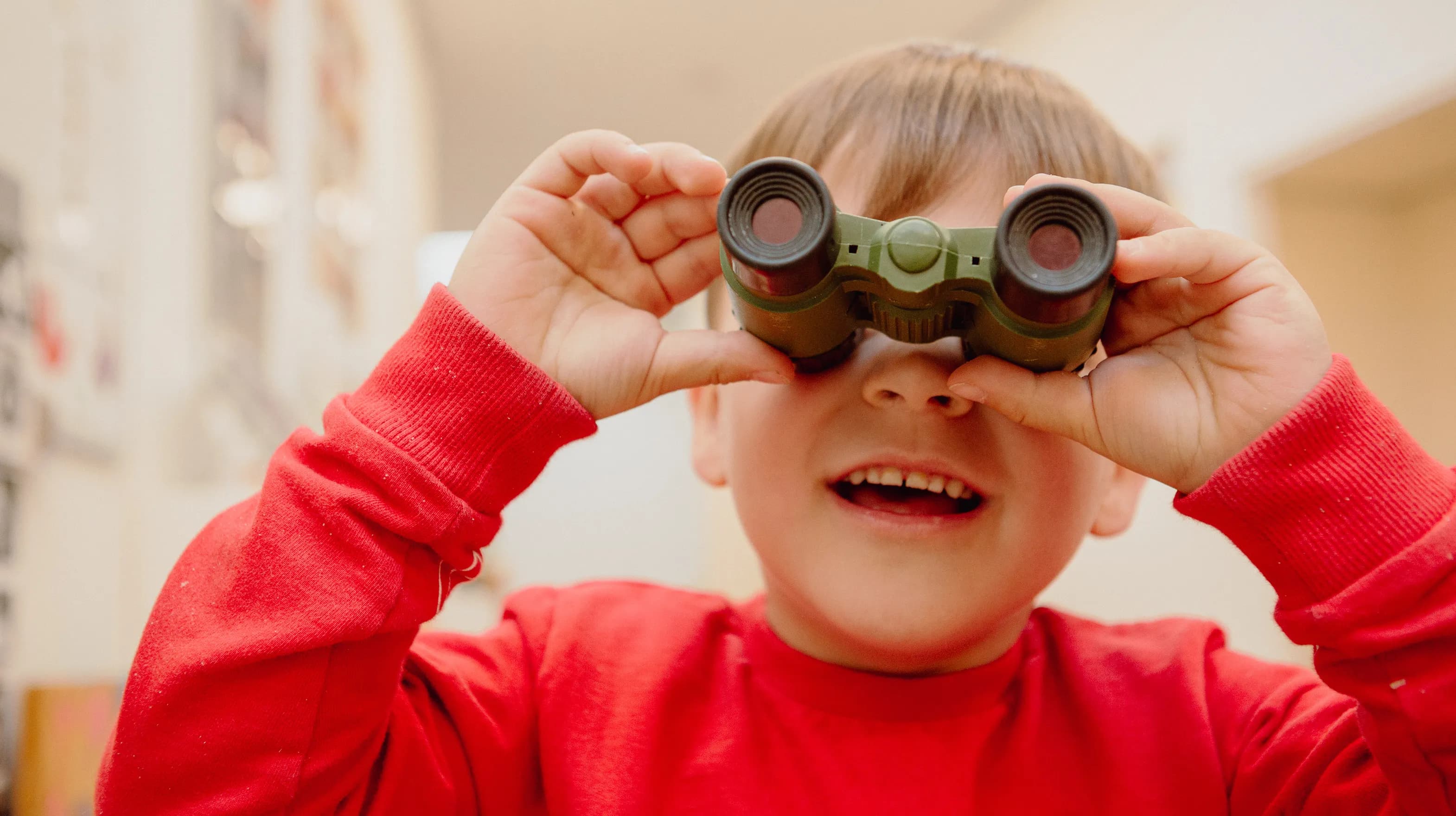 Kind kijkt door een verrekijker bij een Peutergroep van kinderopvang Kind&co ludens