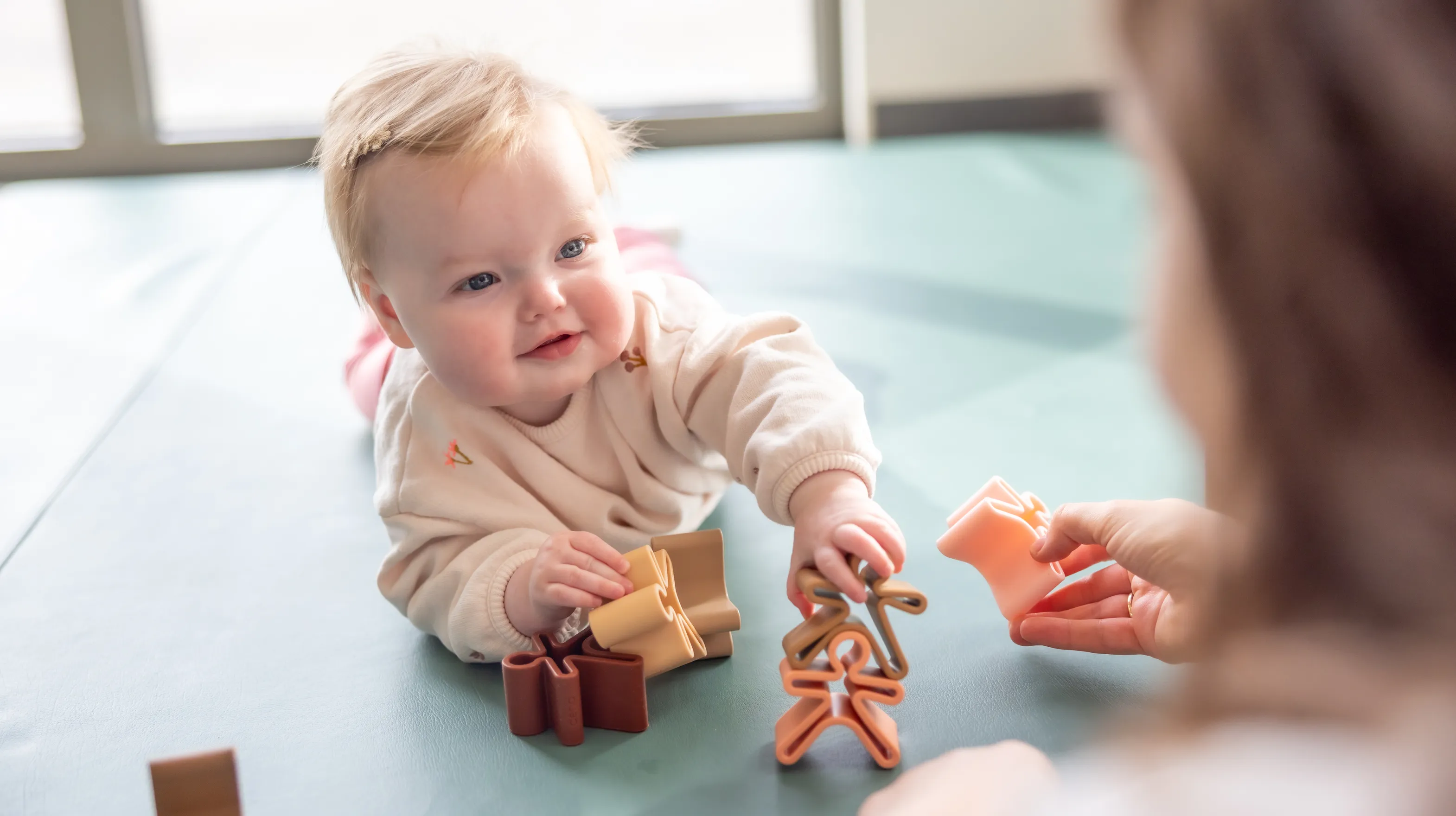Baby speelt met houten speelgoed poppetjes bij gastouder van kinderopvang Kind&co ludens