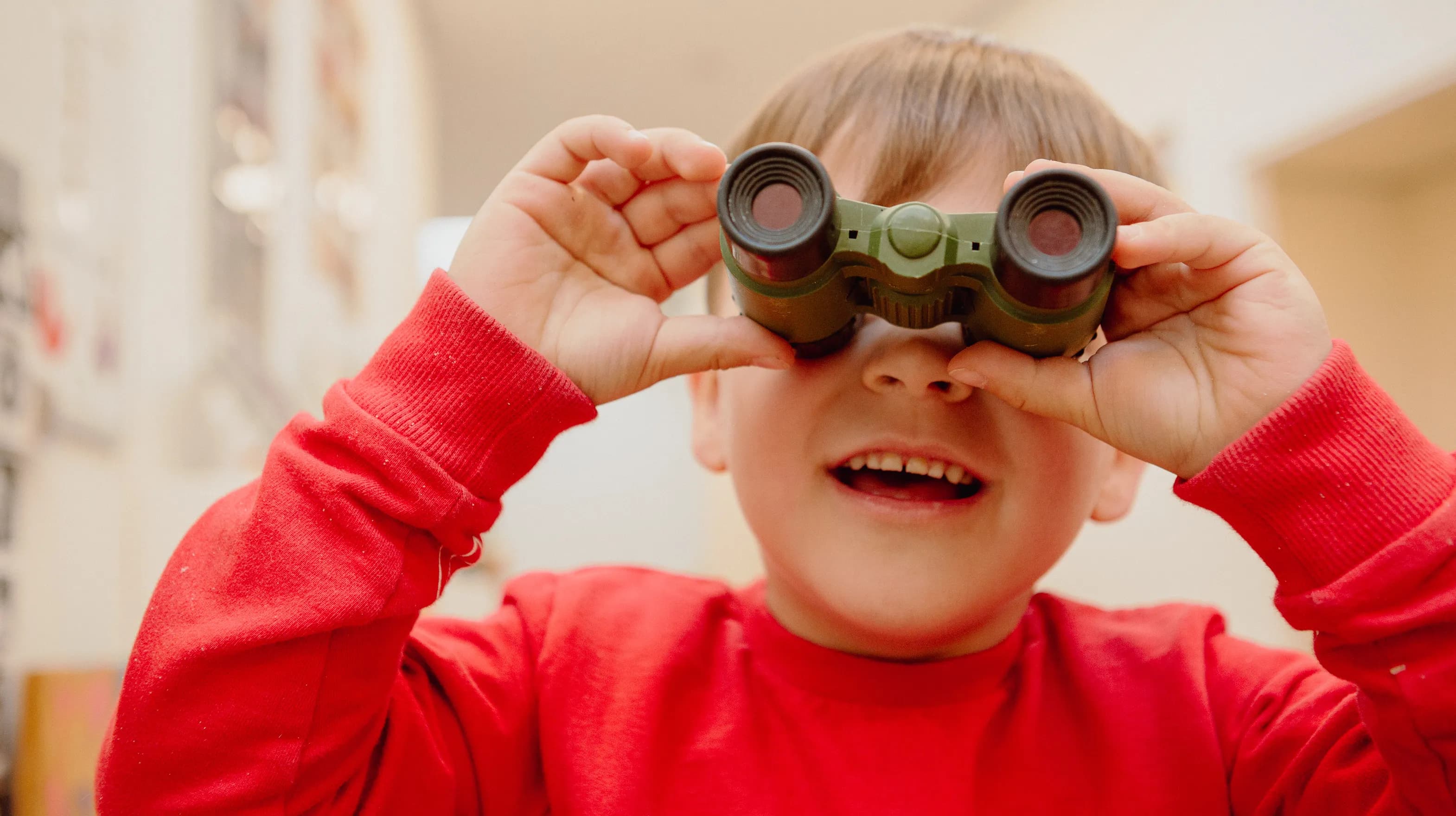 Kind kijkt door een verrekijker bij een Peutergroep van kinderopvang Kind&co ludens