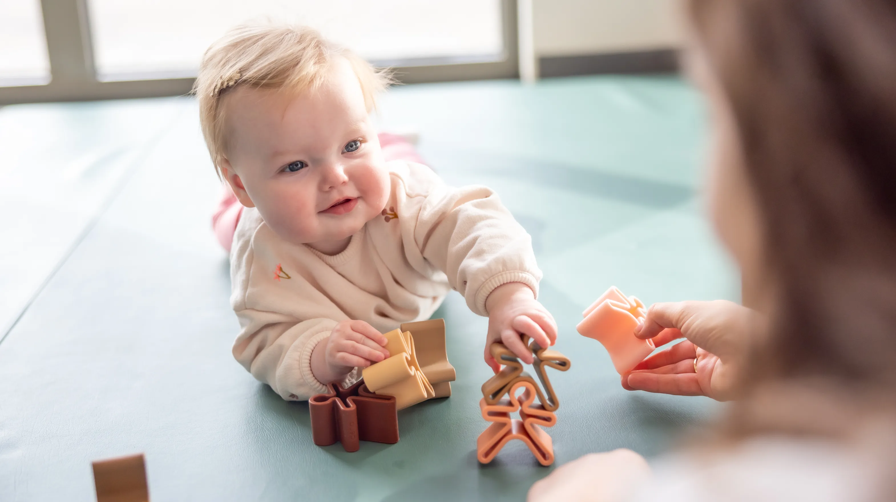 Baby speelt met  houten speelgoed poppetjes bij gastouder van kinderopvang Kind&co ludens