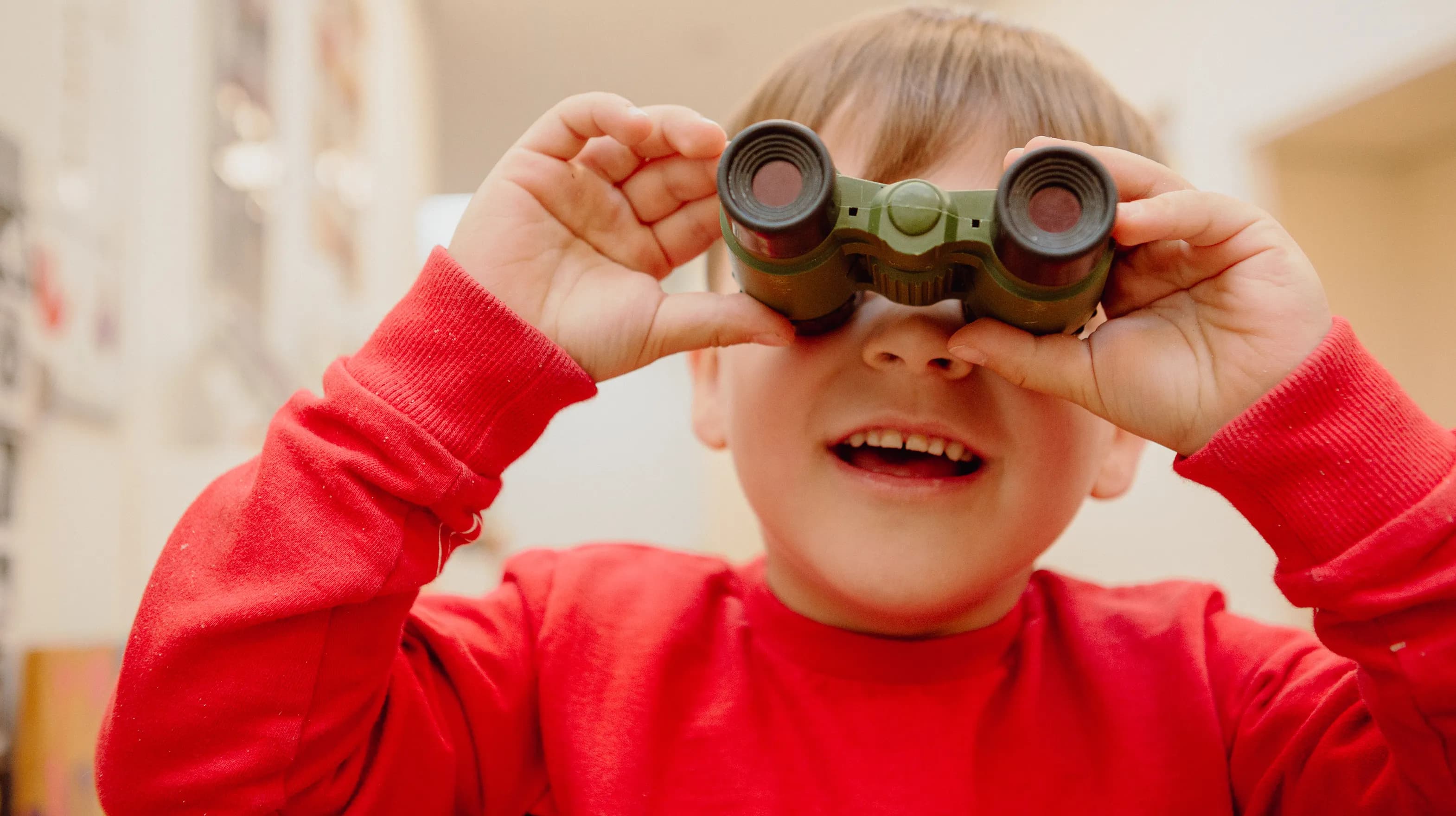 Kind kijkt door een verrekijker bij een Peutergroep van kinderopvang Kind&co ludens