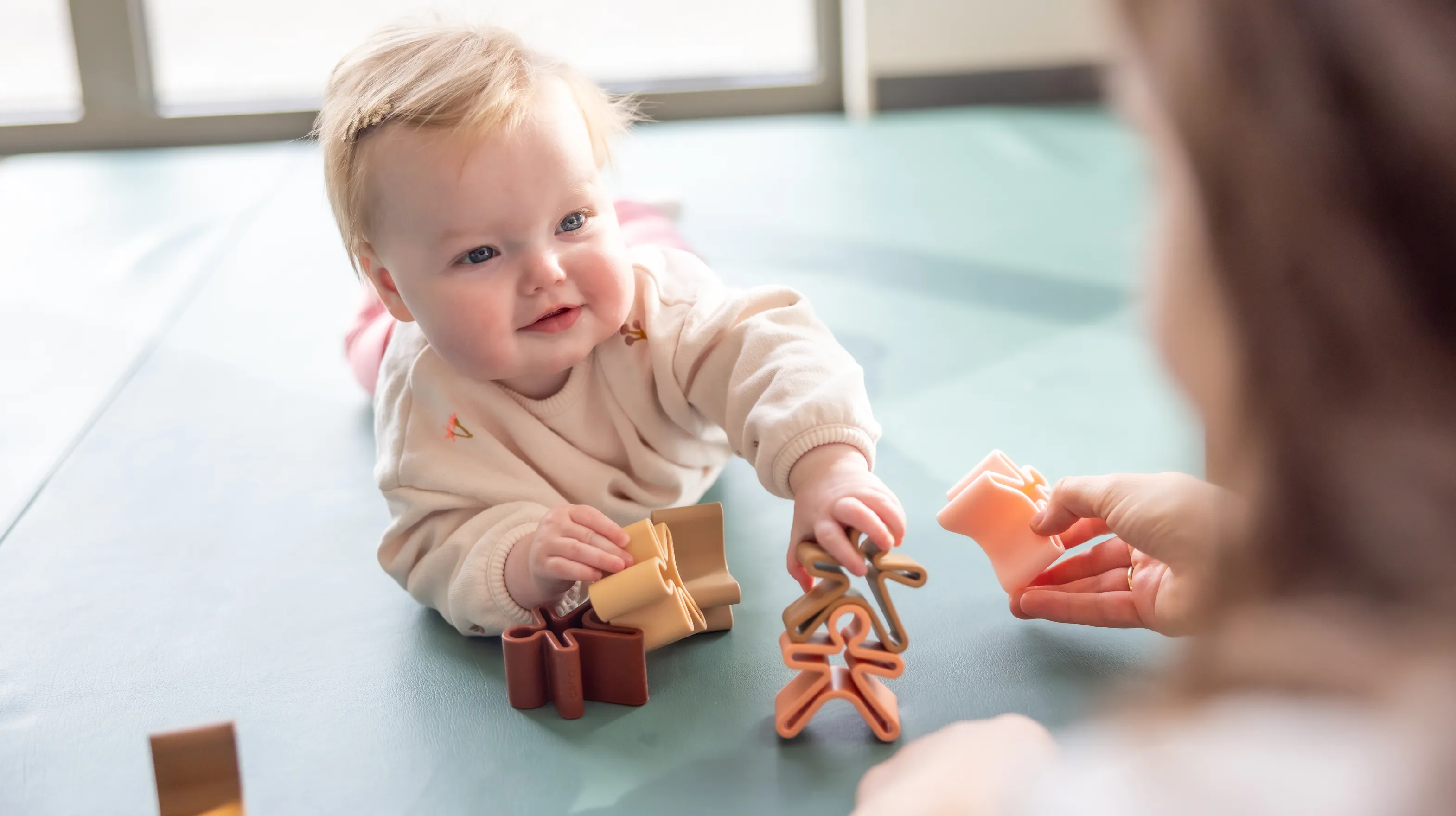 Baby speelt met houten speelgoed poppetjes bij gastouder van kinderopvang Kind&co ludens