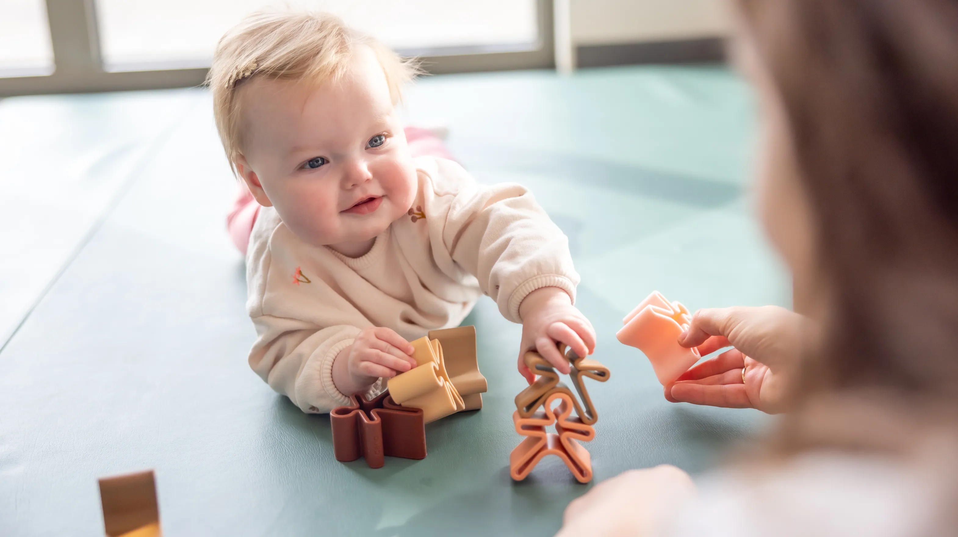 Baby speelt met houten speelgoed poppetjes bij gastouder van kinderopvang Kind&co ludens
