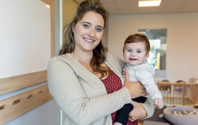 Baby wordt geknuffeld door pedagogisch medewerker bij kinderopvang Kind&co ludens