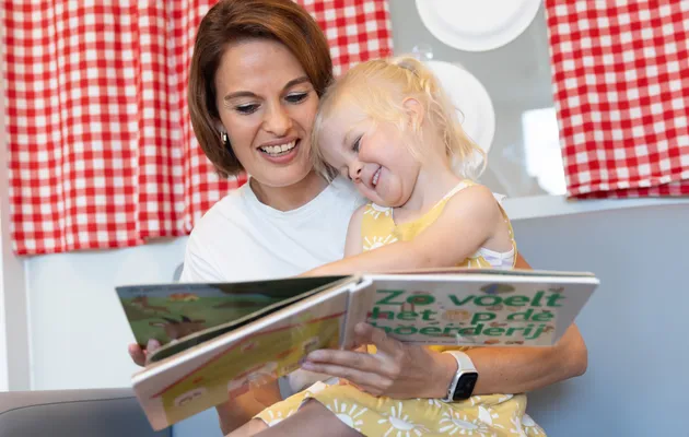 Pedagogisch medewerker leest kind voor bij kinderopvang Kind&co ludens