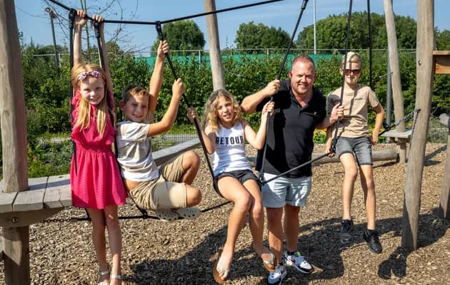 Kinderen spelen buiten met pedagogisch medewerker bij kinderopvang Kind&co ludens