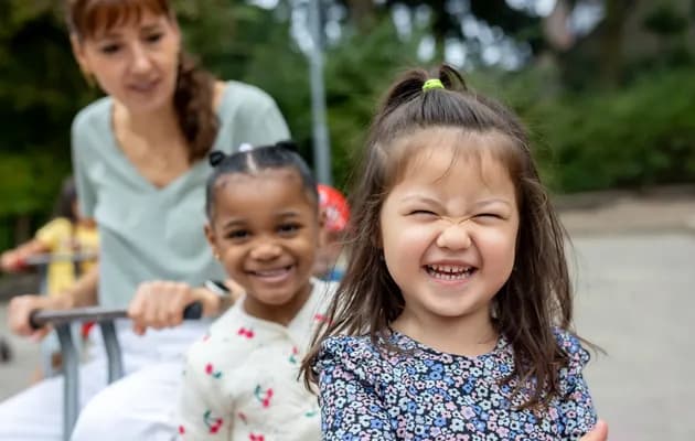 Kinderen spelen buiten met pedagogisch medewerker bij kinderopvang Kind&co ludens