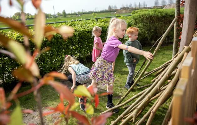 Kinderen bouwen een hut van takken bij kinderopvang Kind&co ludens