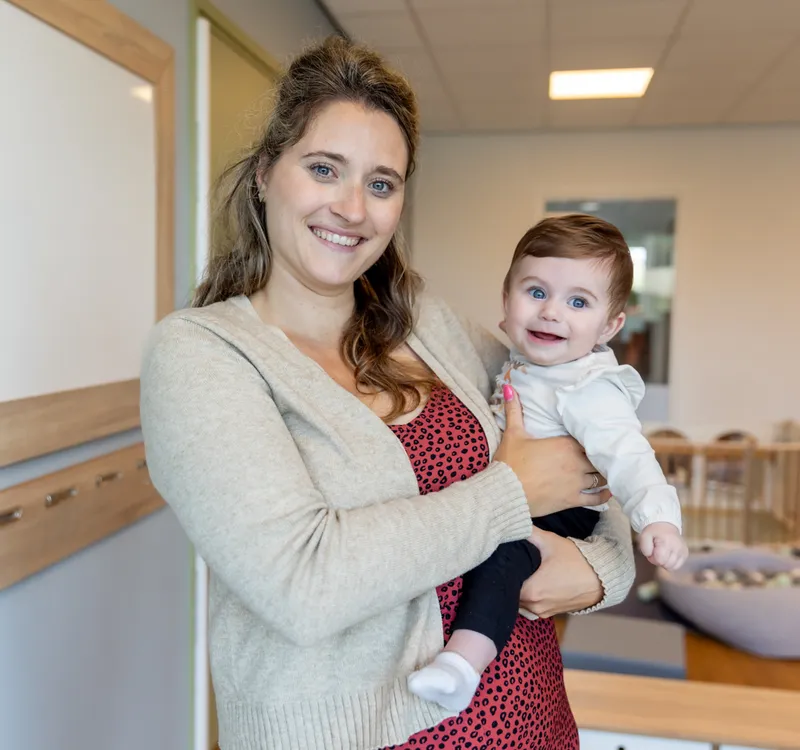 Baby wordt geknuffeld door pedagogisch medewerker bij kinderopvang Kind&co ludens