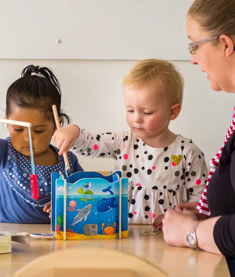 Kinderen spelen samen "Vissen" onder begeleiding van een pedagogisch medewerker bij kinderopvang Kind&co ludens
