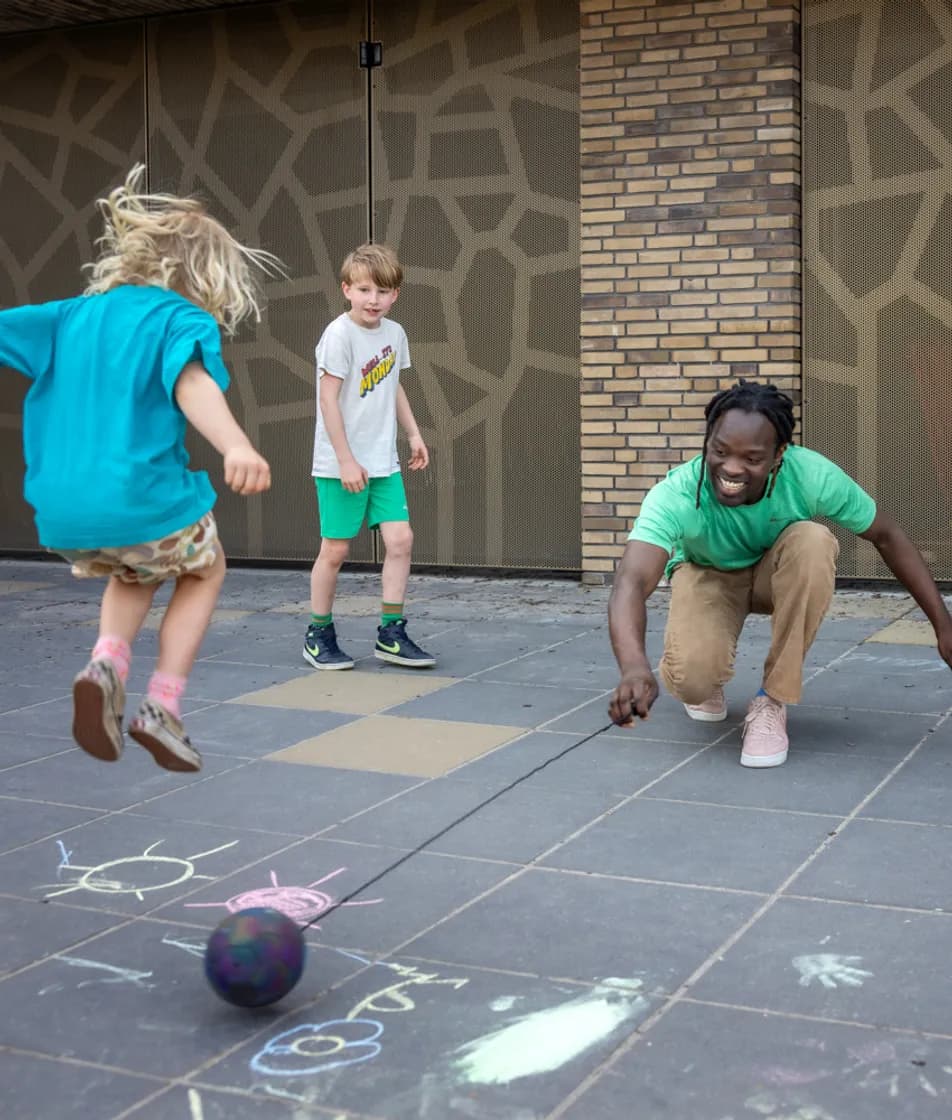 Pedagogisch medewerker speelt balspel met de kinderen bij kinderopvang Kind&co ludens