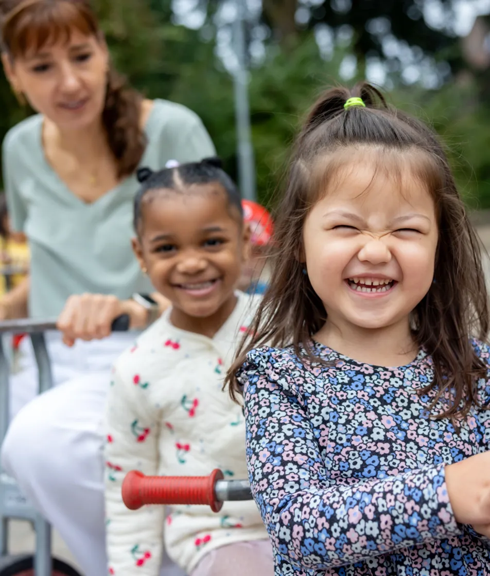 Kinderen spelen buiten met pedagogisch medewerker bij kinderopvang Kind&co ludens