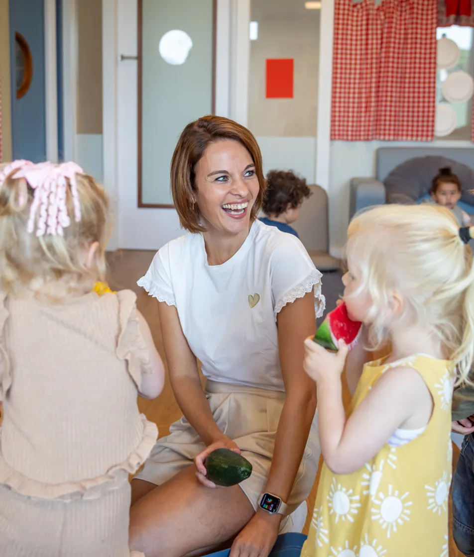 Blije kinderen spelen met pedagogisch medewerker in kinderkeuken bij kinderopvang Kind&co ludens