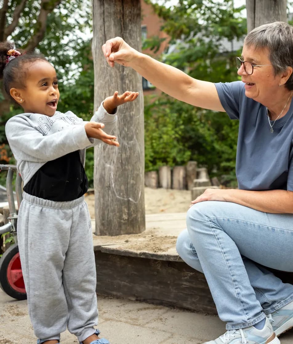 Kind speelt buiten met pedagogisch medewerker bij kinderopvang Kind&co ludens