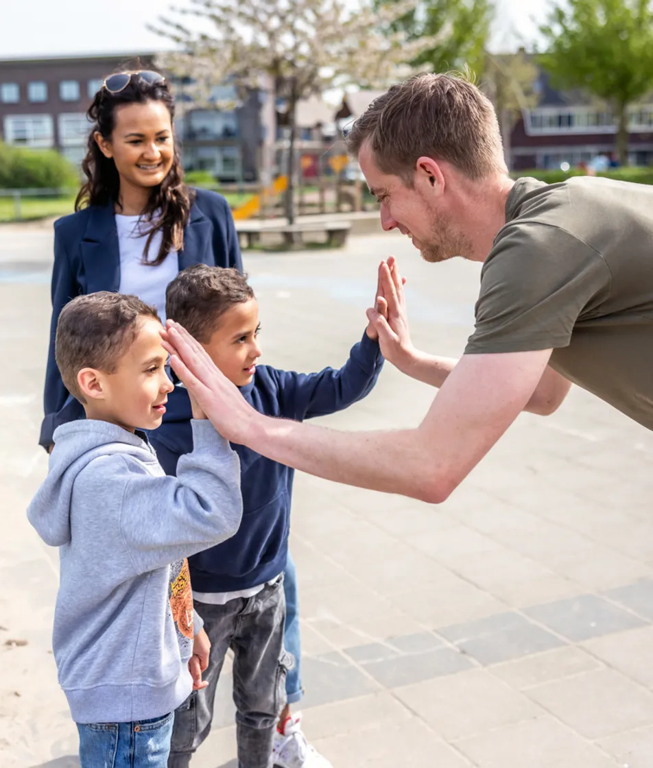 Pedagogisch medewerker geeft een high five bij kinderopvang Kind&co ludens