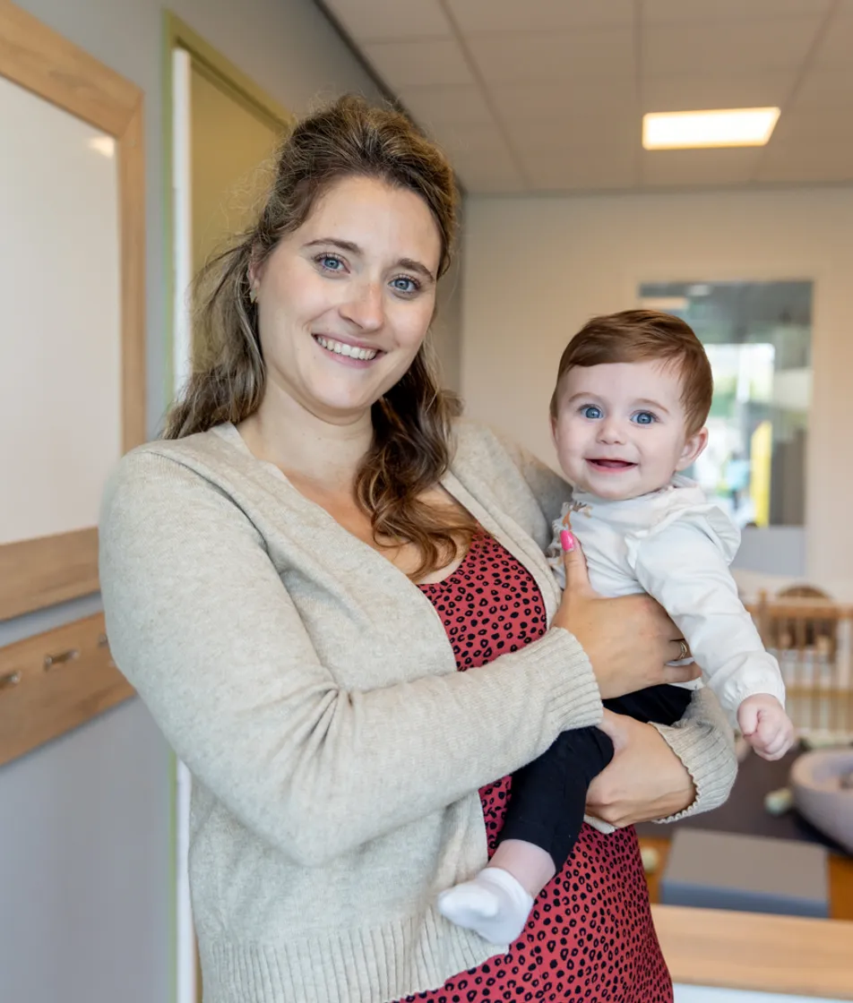 Baby wordt geknuffeld door pedagogisch medewerker bij kinderopvang Kind&co ludens