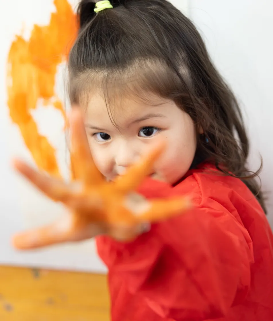 Blij kind verft met haar handen bij kinderopvang Kind&co ludens