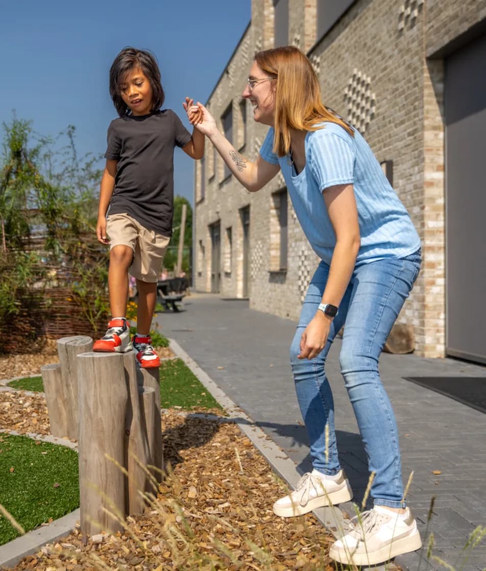 Kind speelt buiten met pedagogisch medewerker bij kinderopvang Kind&co ludens