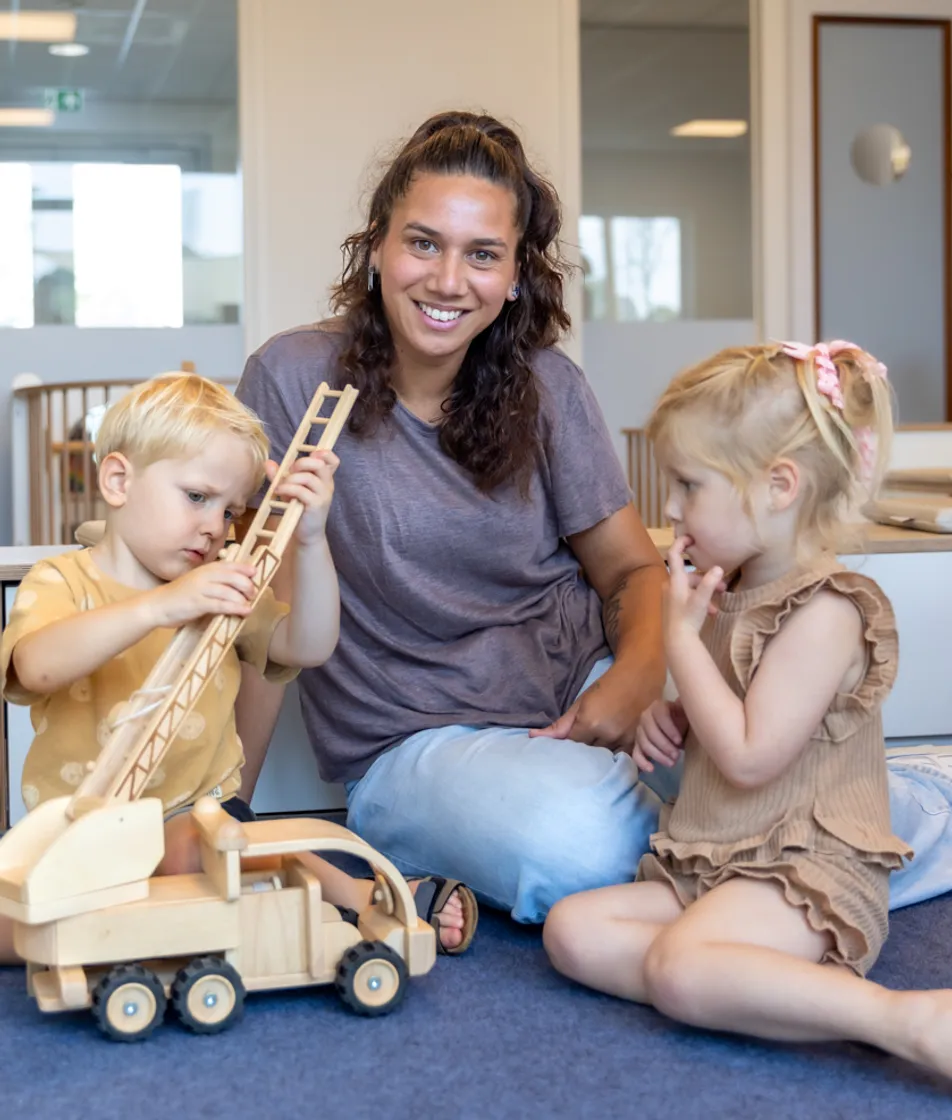Kinderen spelen samen met pedagogisch medewerker bij kinderopvang Kind&co ludens