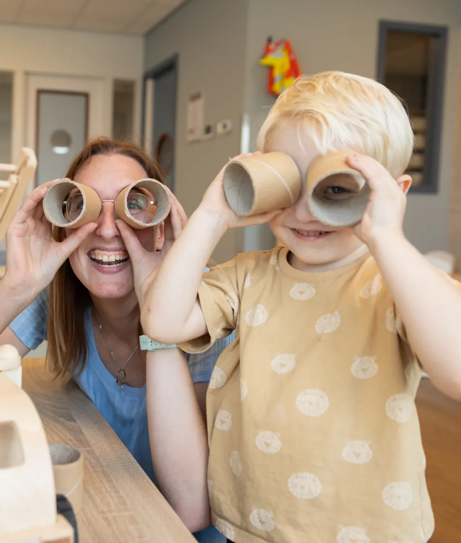 Kind speelt met wc rollen met pedagogisch medewerker bij kinderopvang Kind&co ludens