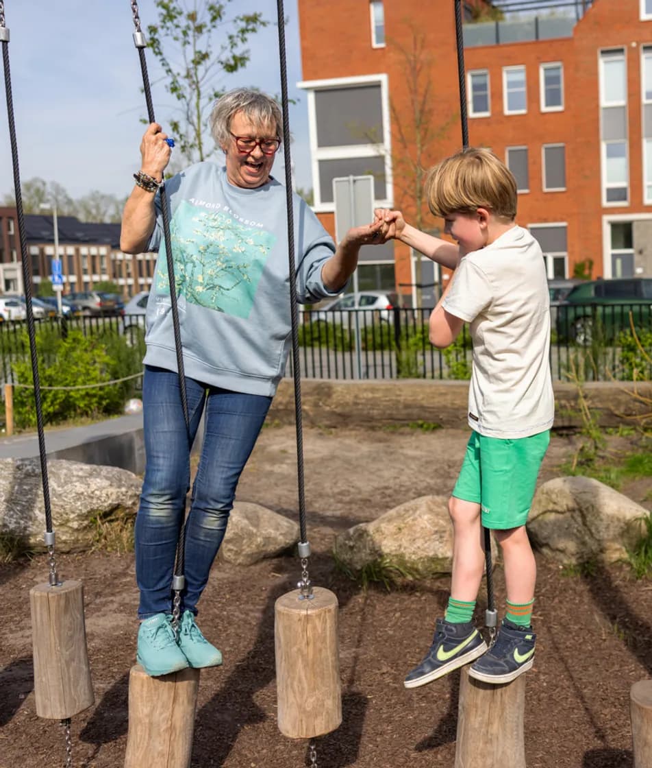 Kind en pedagogisch medewerker spelen buiten op balansblokken bij kinderopvang Kind&co ludens