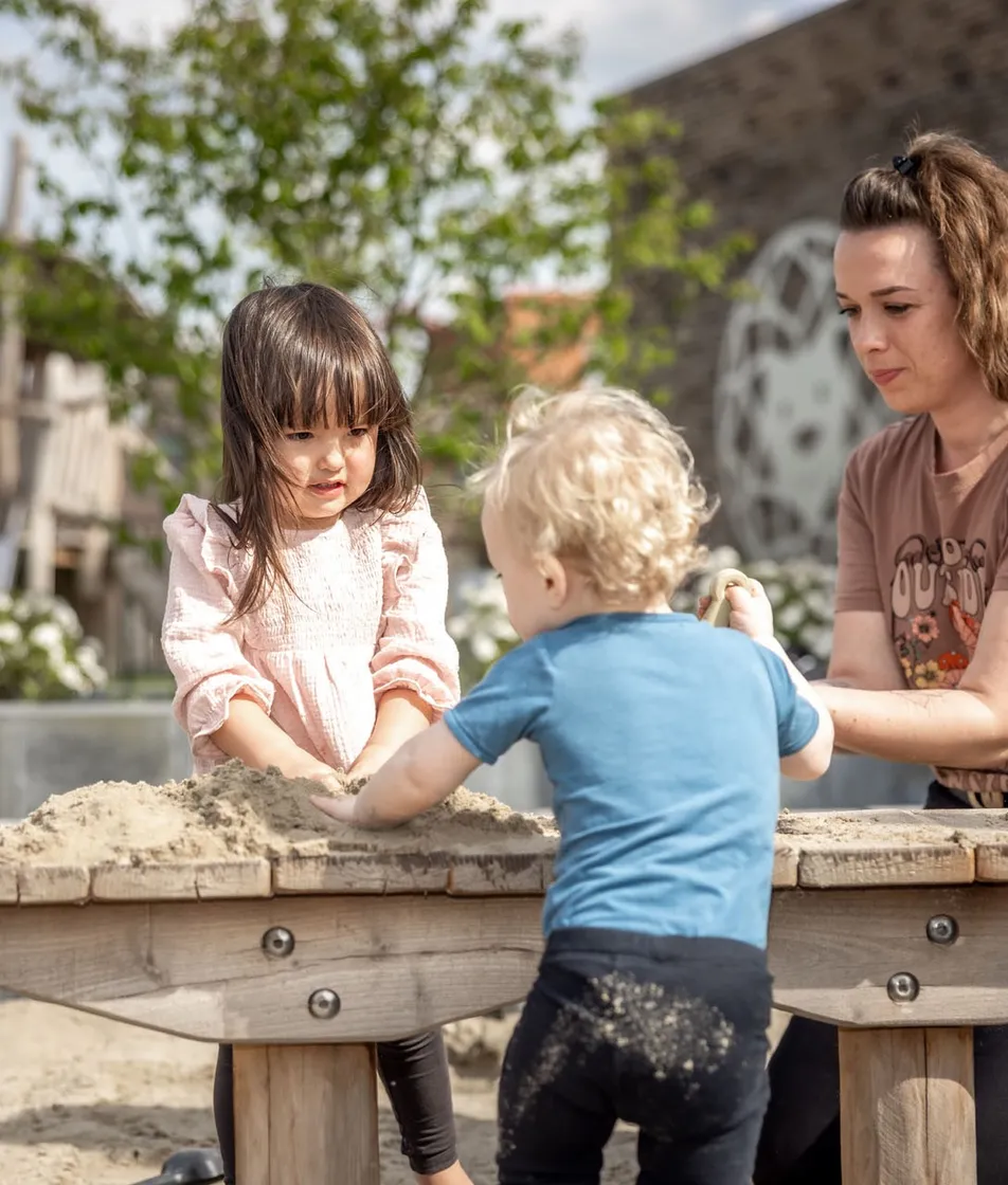 Kinderen spelen in zandbak met pedagogisch medewerker bij Kind&co ludens