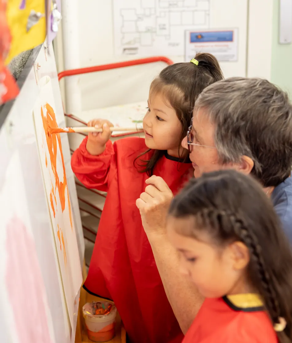 Kinderen verven met pedagogisch medewerker bij kinderopvang Kind&co ludens