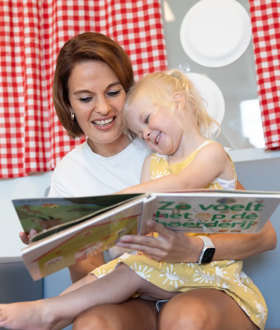 Pedagogisch medewerker leest kind voor bij kinderopvang Kind&co ludens
