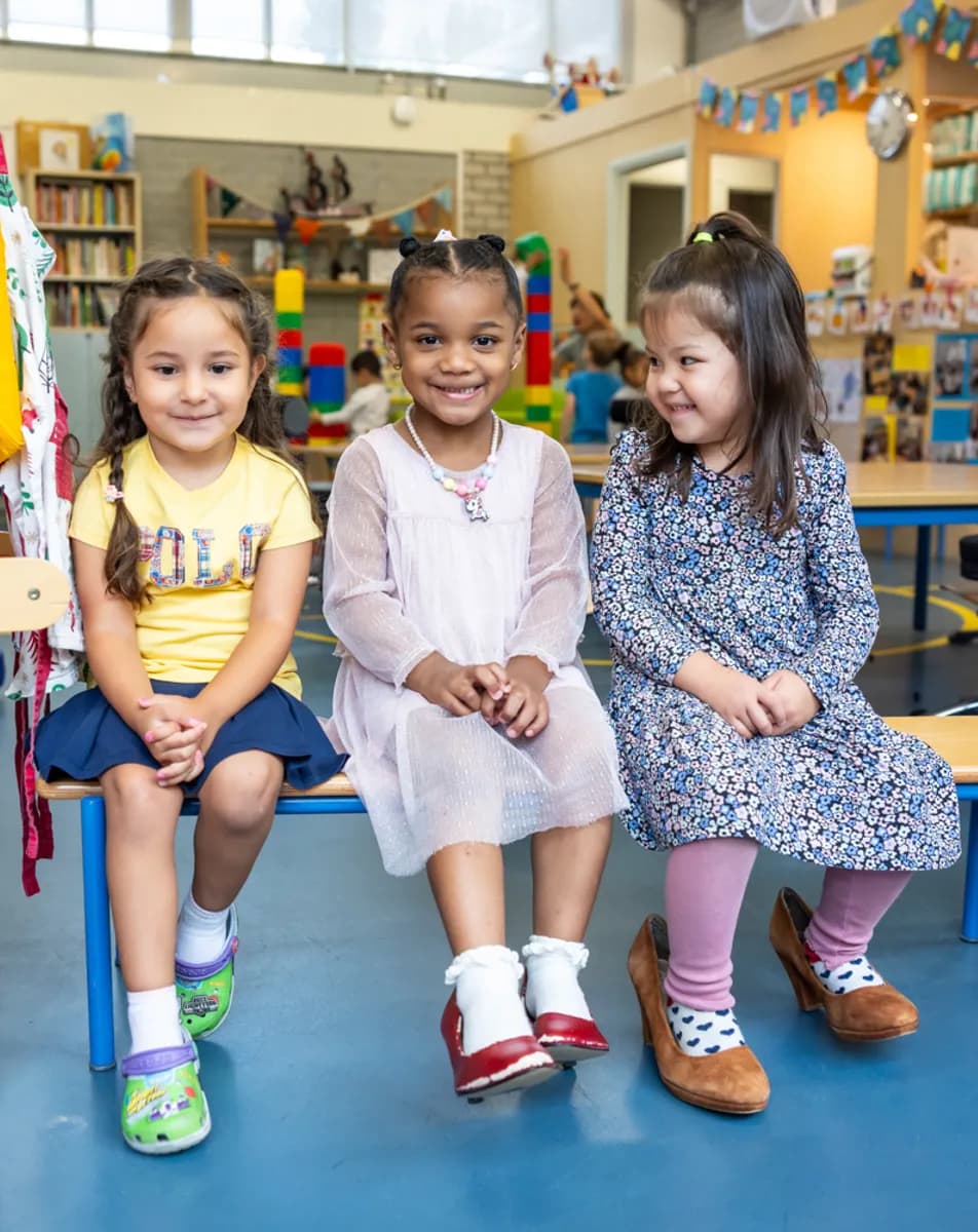Kinderen zitten samen op een bankje bij kinderopvang Kind&co ludens