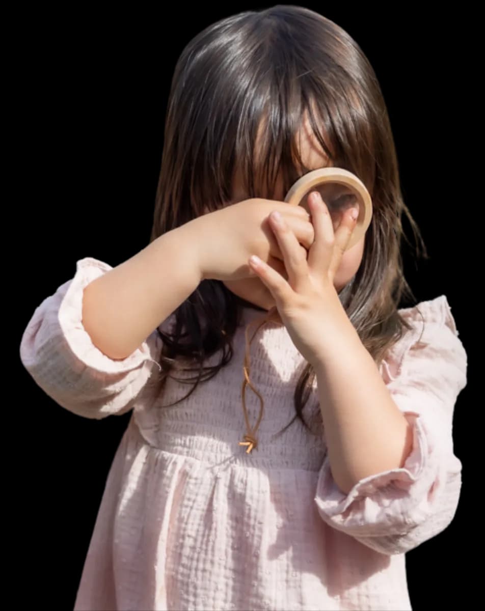 Kind kijkt door vergrootglas bij kinderopvang Kind&co ludens