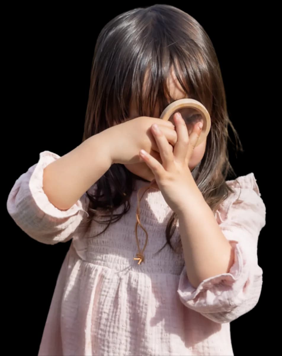 Kind kijkt door vergrootglas bij kinderopvang Kind&co ludens
