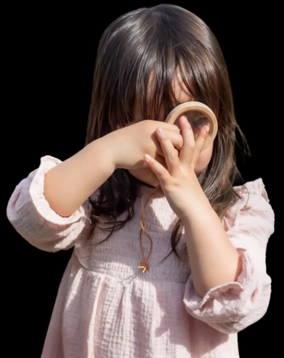 Kind kijkt door vergrootglas bij kinderopvang Kind&co ludens